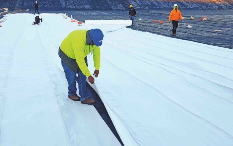 A man laying Geoquest engineering's geosynthetic drainage solution , DrainTube, at a mine site.